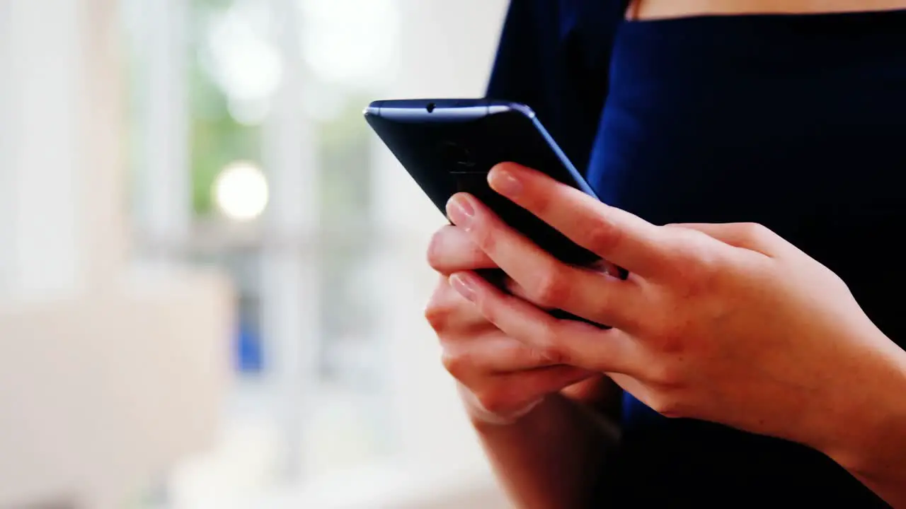 Female business executive text messaging on mobile phone