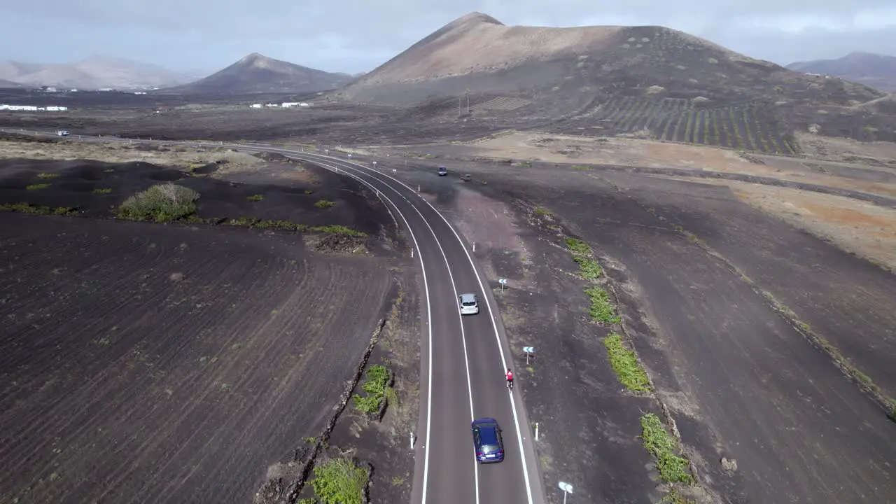 aerial shot of moving cloud's shadows cars overtaking biker in Lanzarote island