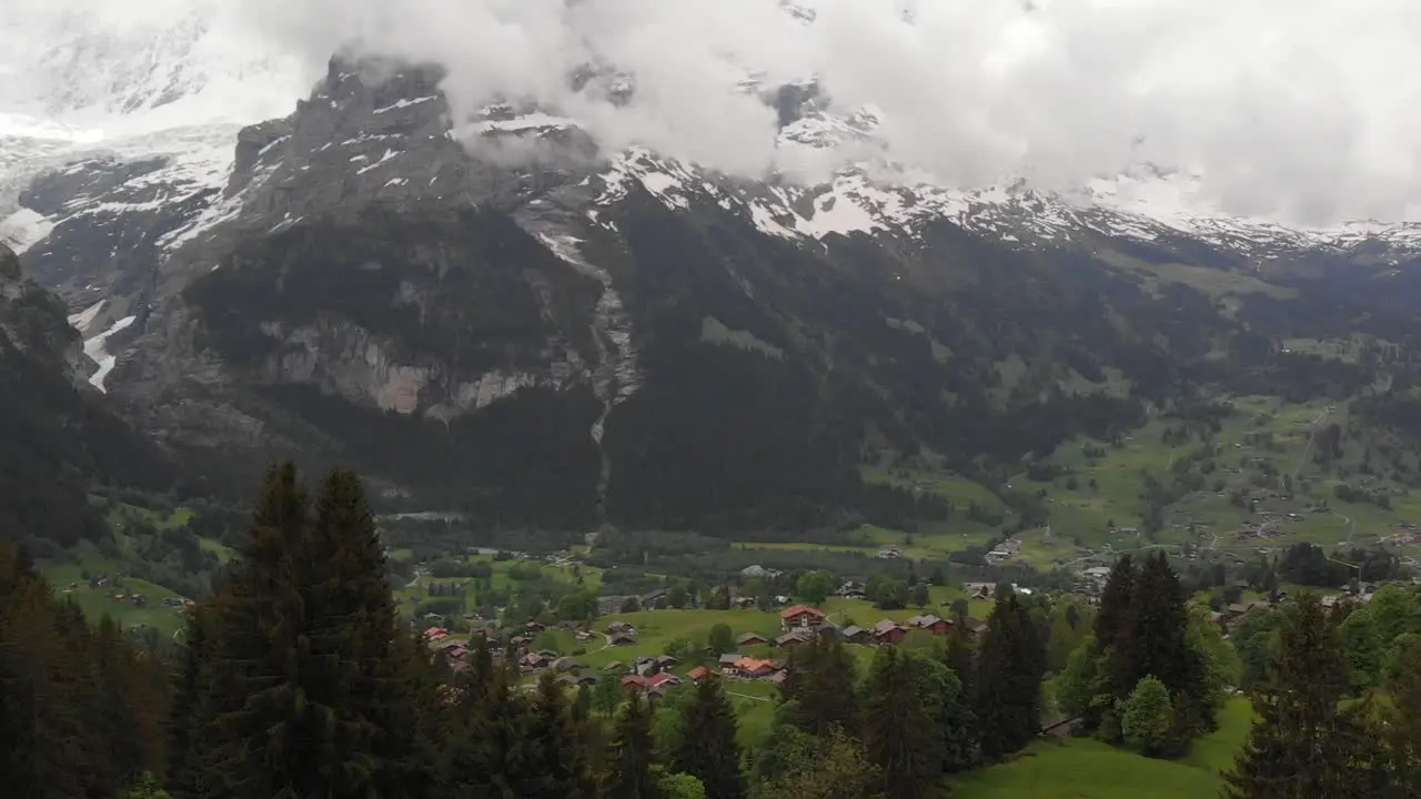 Aerial of a Swiss Grassy Valley with Mountain Ranges in Background