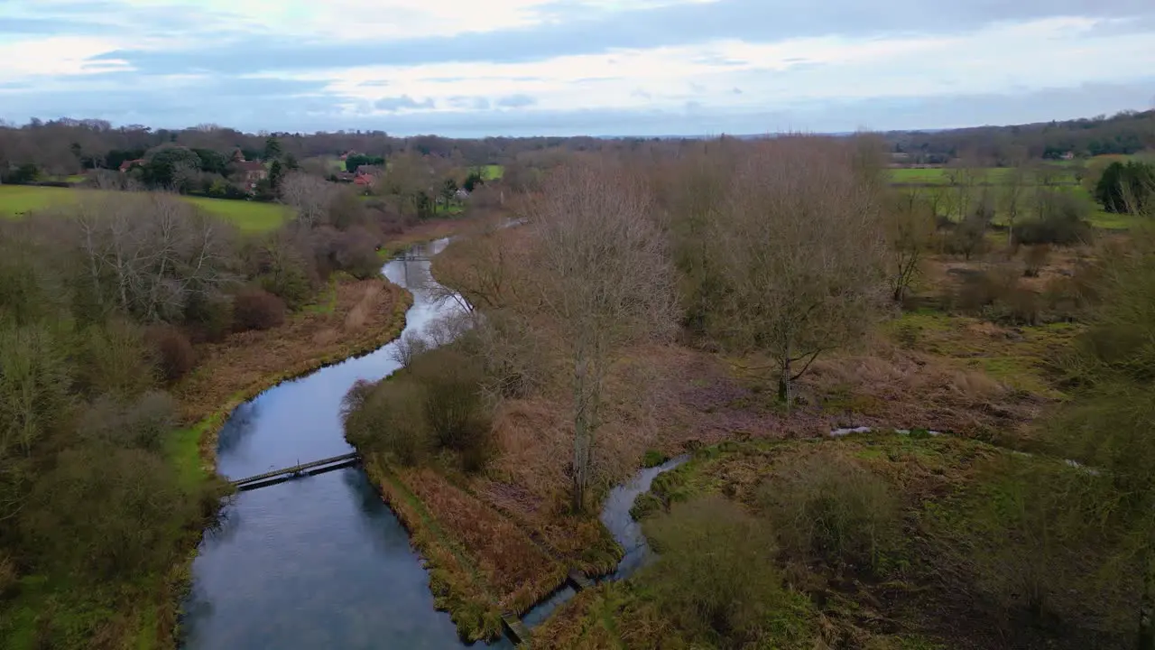 Flight following river in lush green Southdowns countryside in winter no leaves on trees but bright sunny day