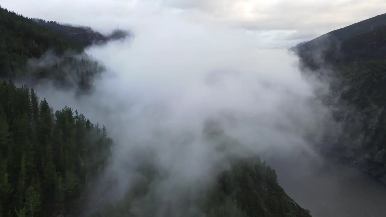 Flying towards clouds with a view over a lake mountain and a forest