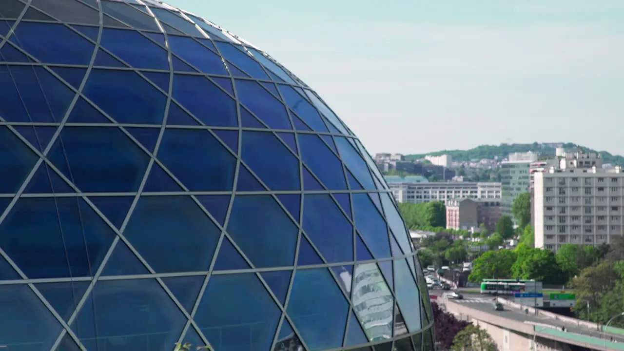 A closer look at the modern glass dome structure of the Seine Musicale concert hall in Paris France with traffic in the background