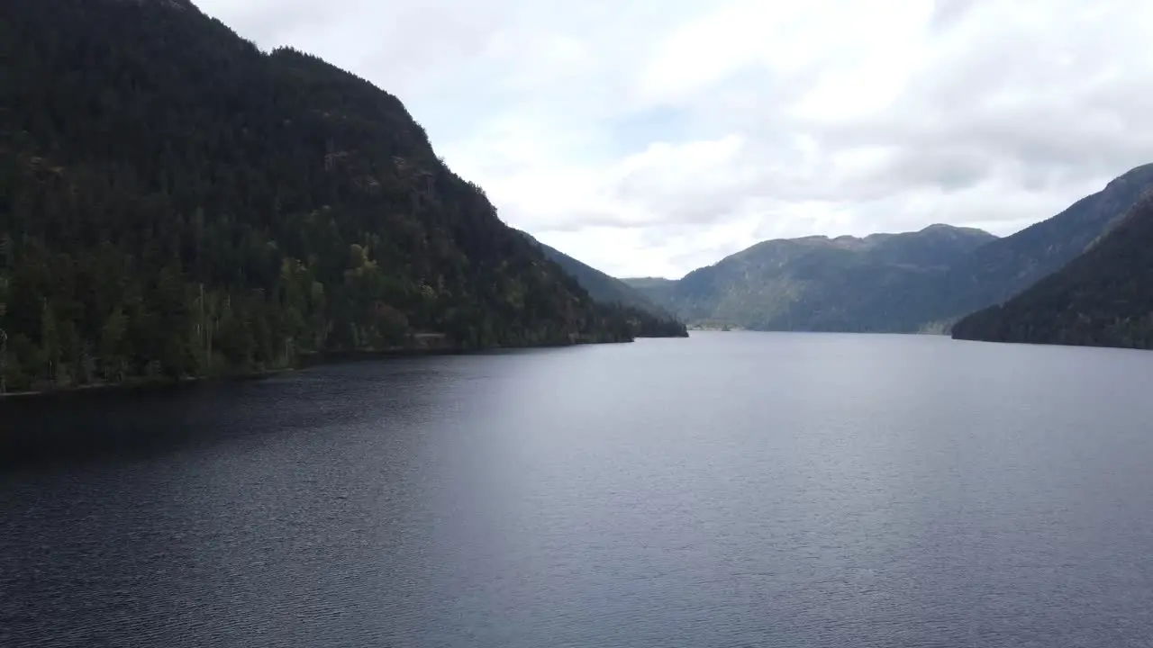 A panning drone video over a lake between two mountains on a sunny day