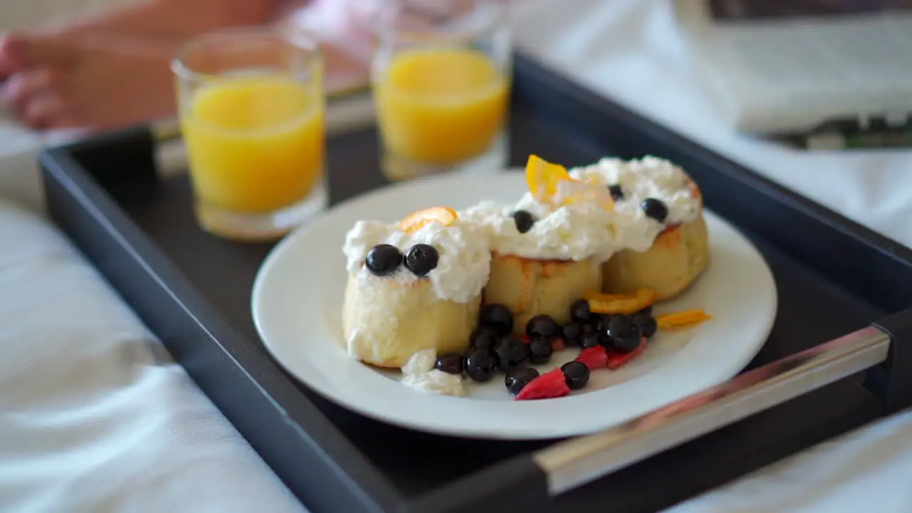 Room service pancakes and orange juice on the edge of a bed in a hotel room