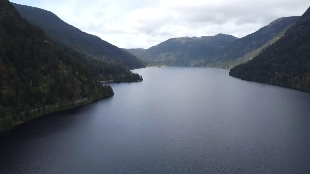 A tilting drone video revealing a lake between two mountains on a sunny day