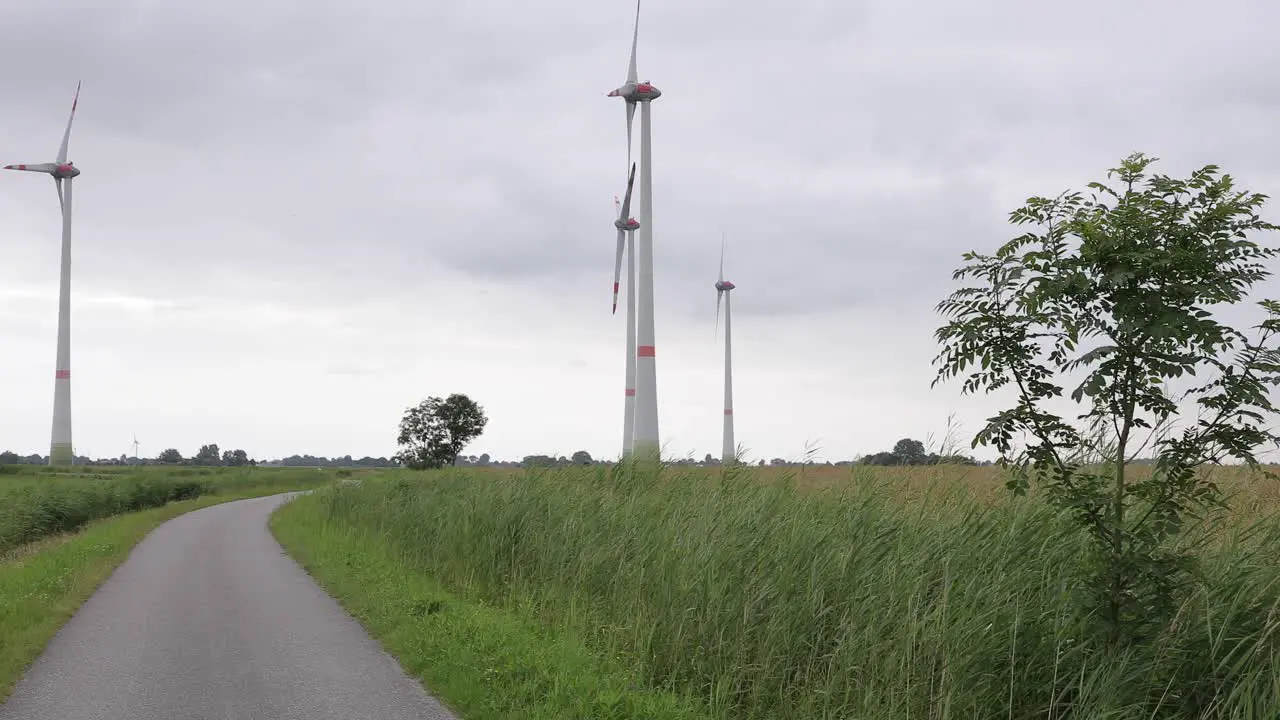 Small street with grass and windmills in background on a dark cloudy day