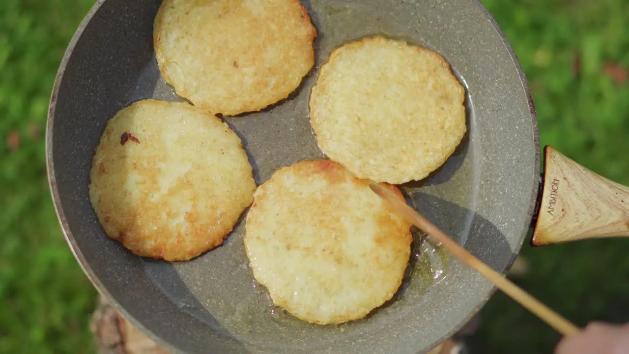 Potato pancakes baking in a pan with oil outside during the summer