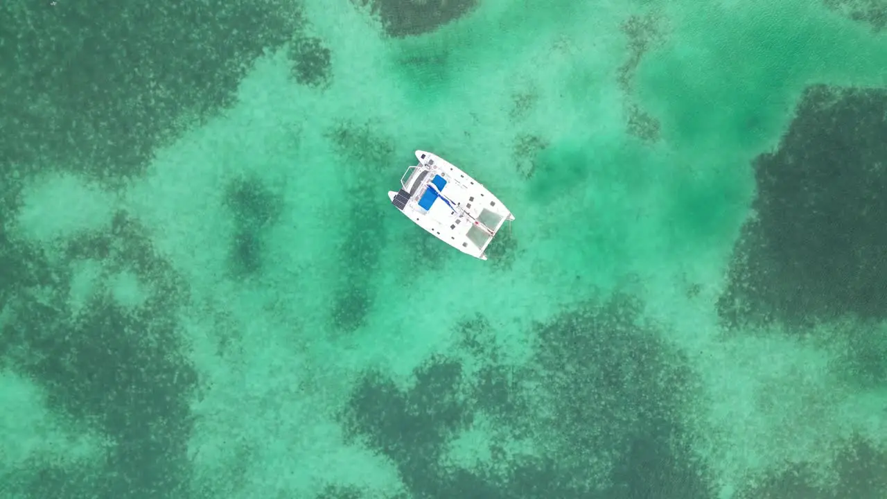 Drone view in Belize flying still over caribbean dark and light blue sea top view shallow water coral reef and a boat