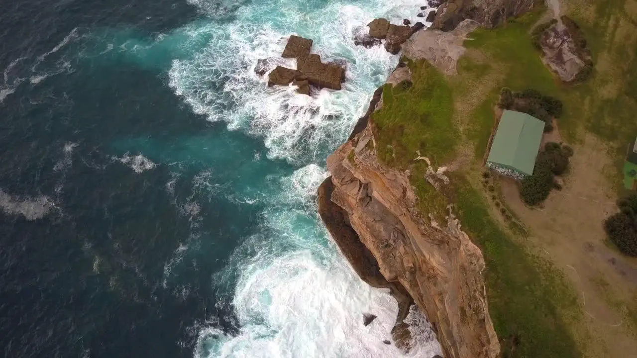 Ocean waves crashing and hitting against cliff and rocks bird eye view aerial drone shot