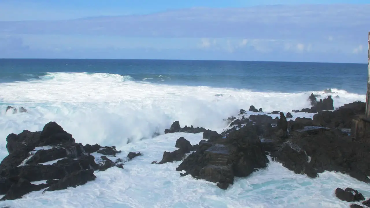 A big waves of the Atlantic Ocean breaks on a rocky coast on a sunny day during a storm in Puerto de la Cruz in the Canaries  wide handheld shot