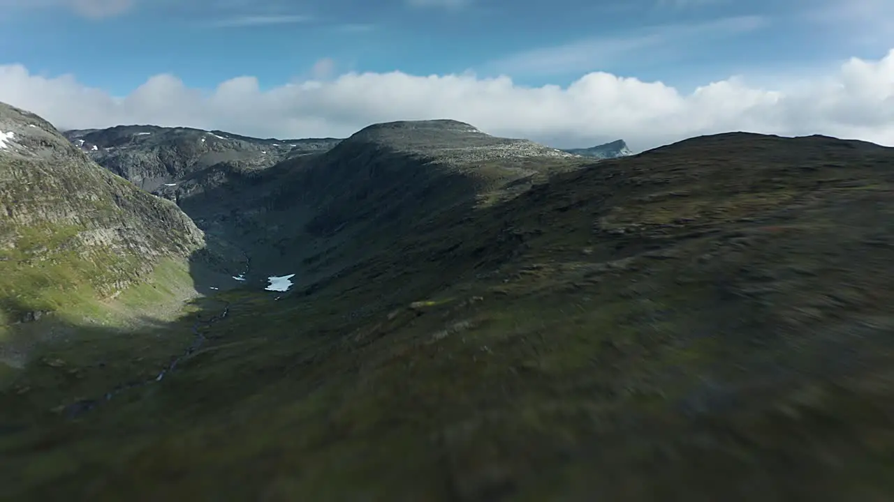 A fast forward flight over the stark northern landscape of the Aurlandsfjellet mountain glacier plateau with dense stormy clouds hovering above