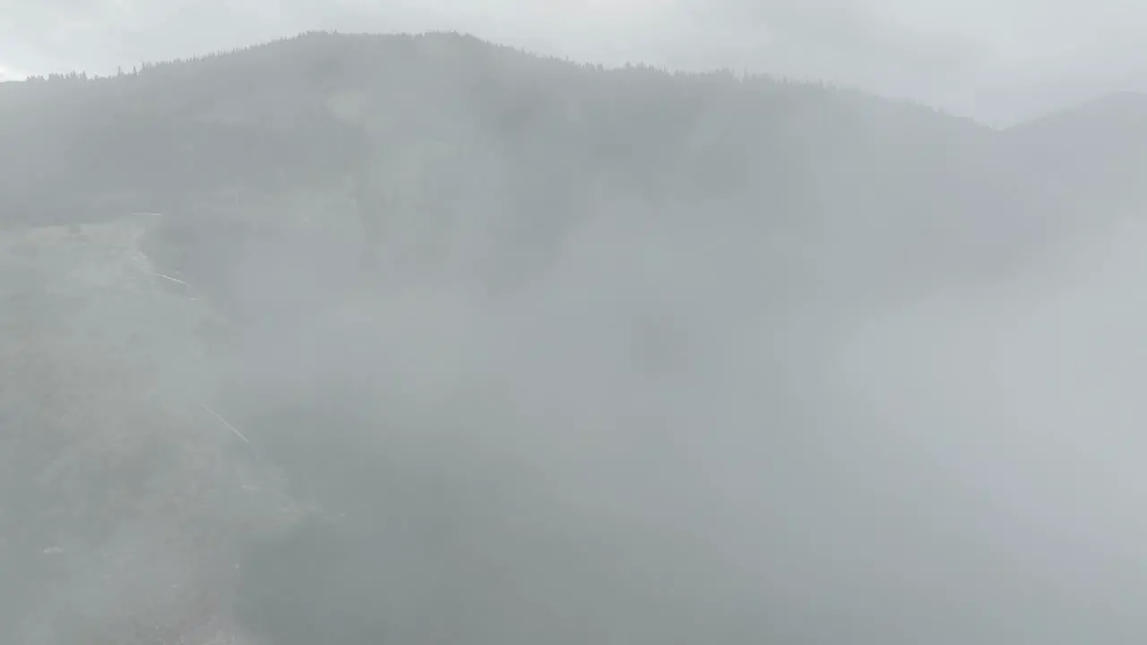 Aerial of low fog hanging over mountain and forest trees