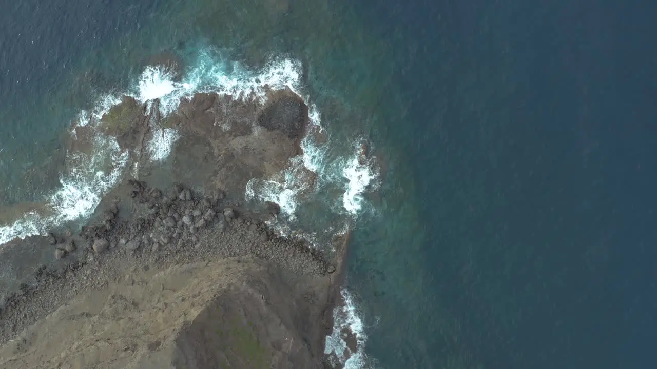 Drone top down shot of waves bounce on rocks at the rocky coast