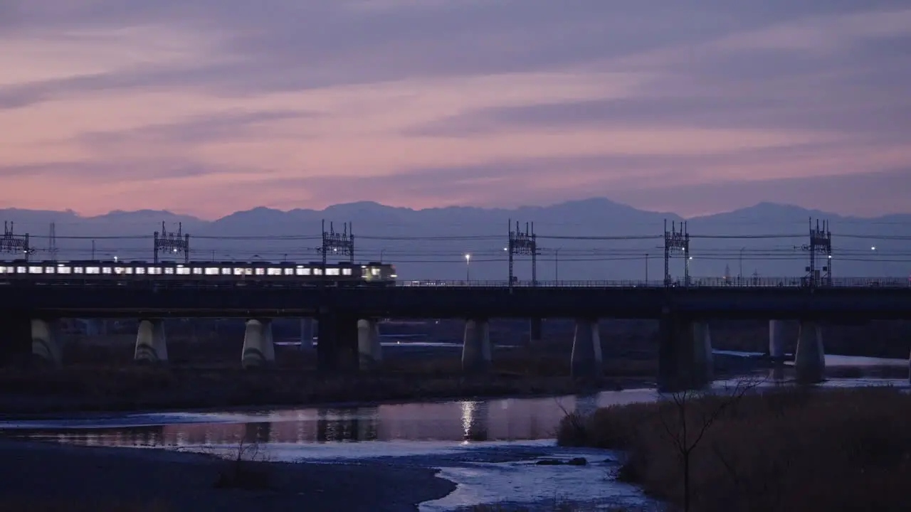 Japanese Train Passing By Futakotamagawa River With Reflection On Water During Beautiful Twilight In Tokyo Japan