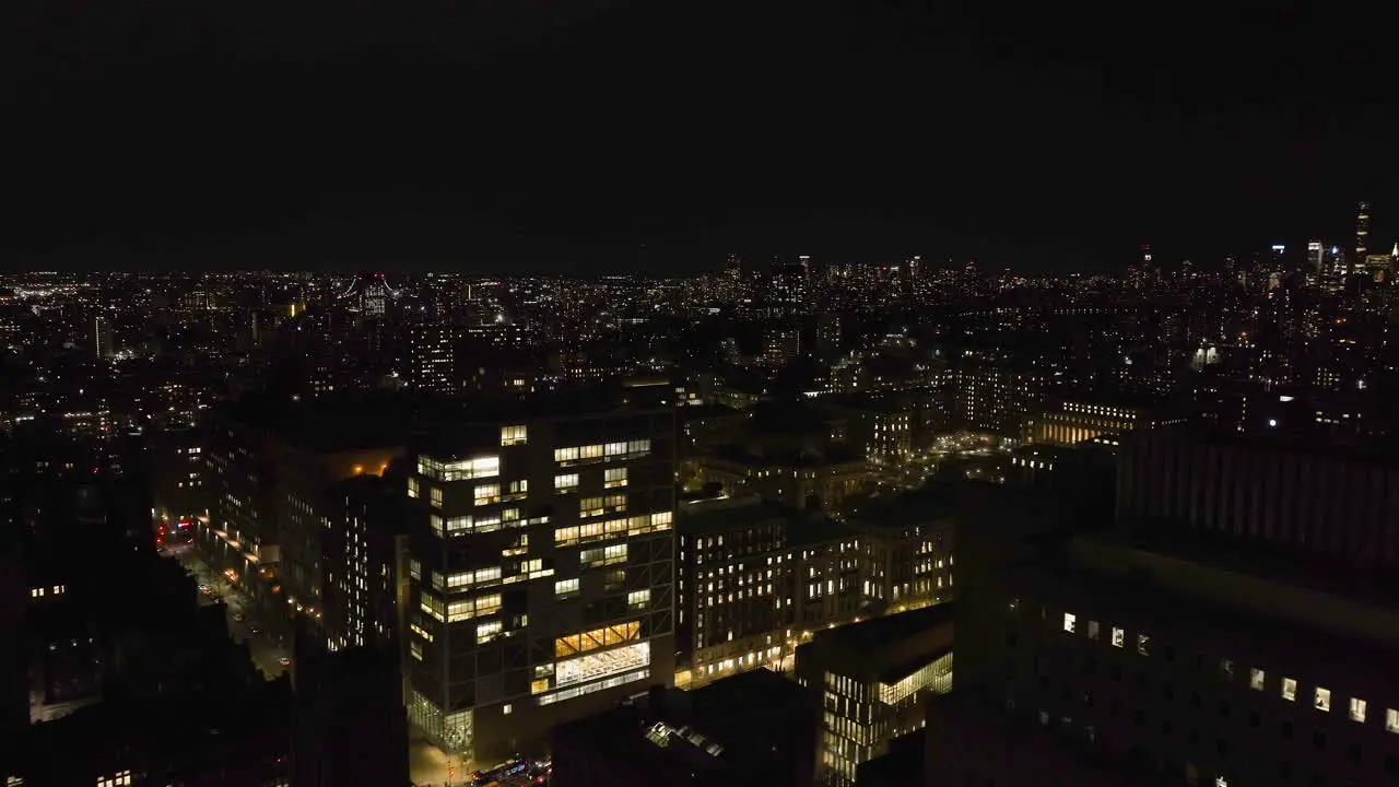 Drone shot flying past the Riverside church and over the illuminated Manhattan cityscape nighttime in NY USA