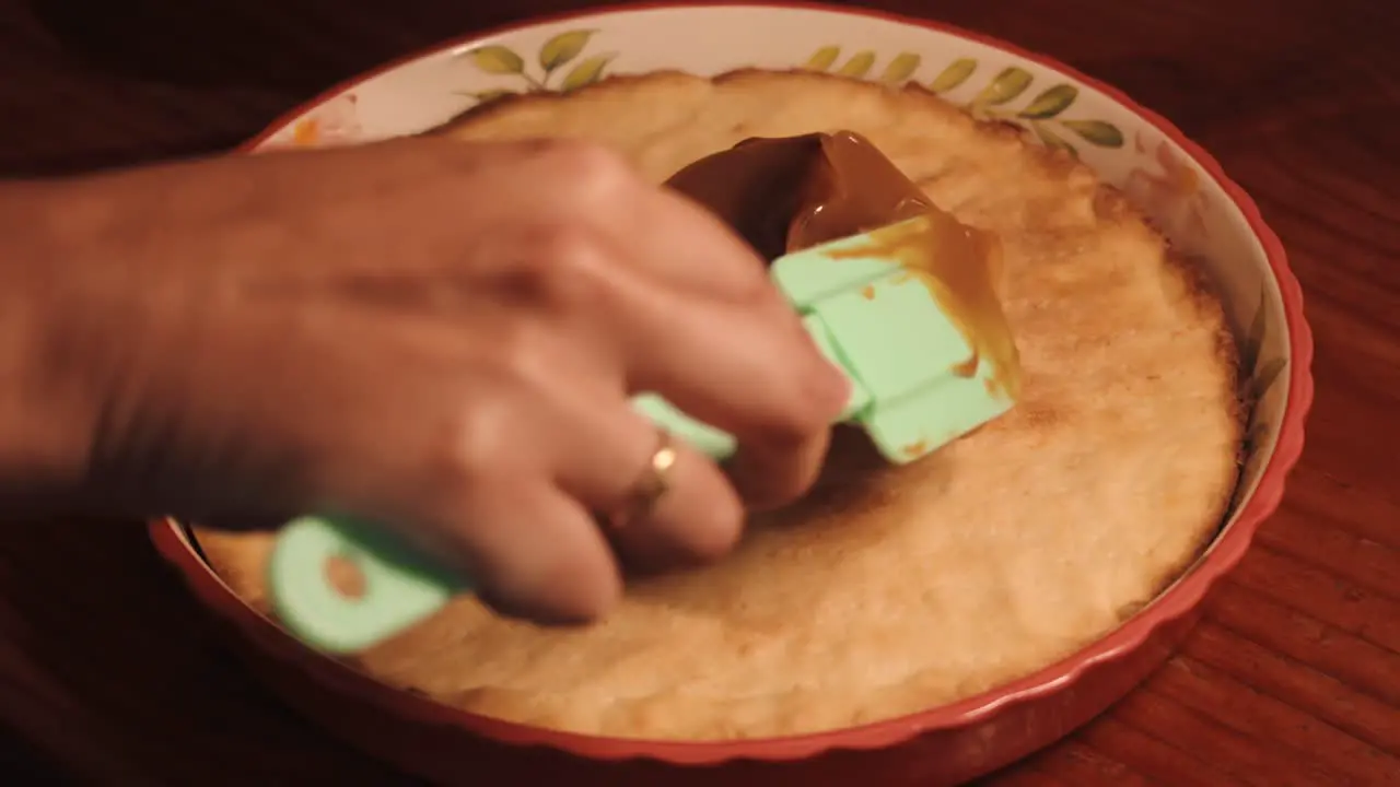 Spreading dulce de leche on a cake base