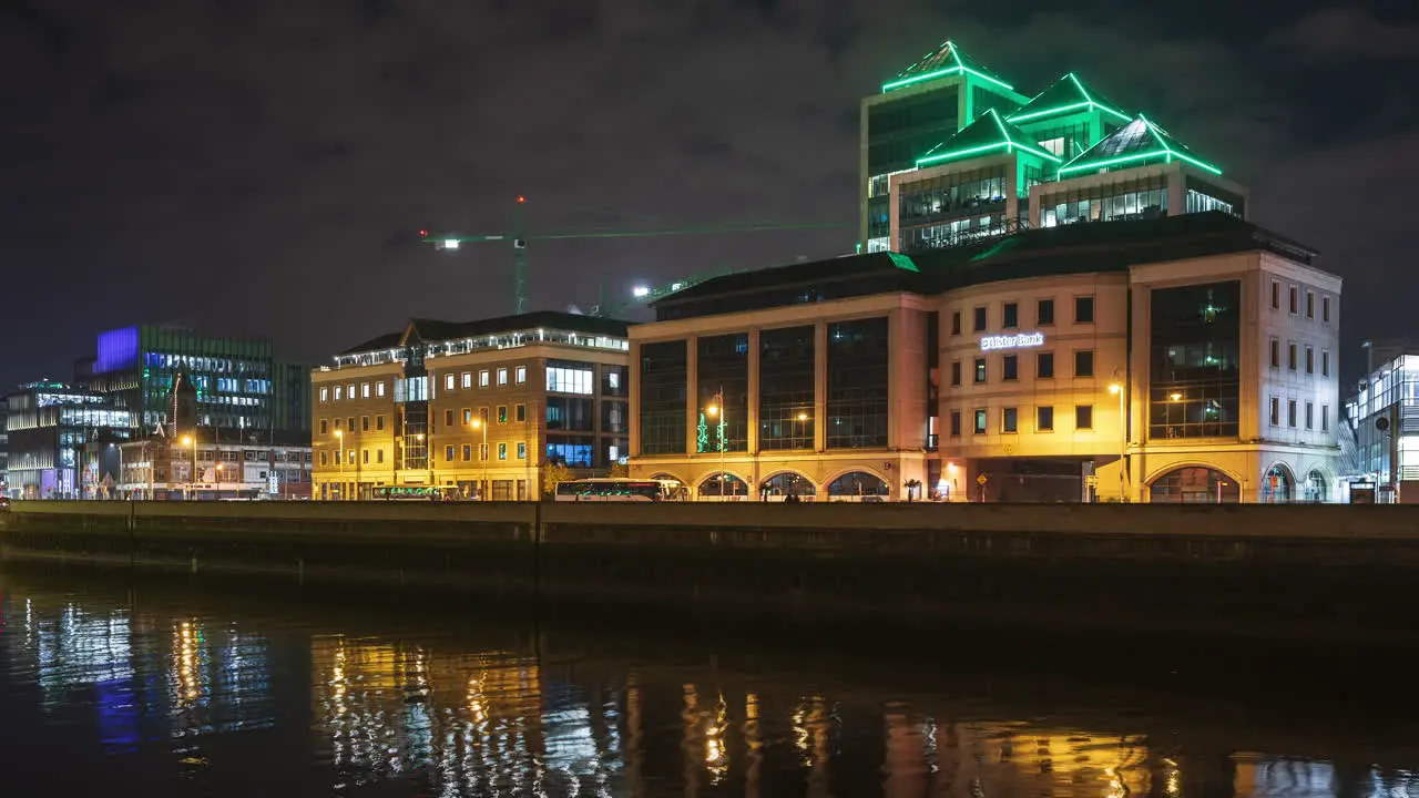 Time lapse of Ulster Bank building illuminated at night with traffic along Liffey river in Dublin City in Ireland