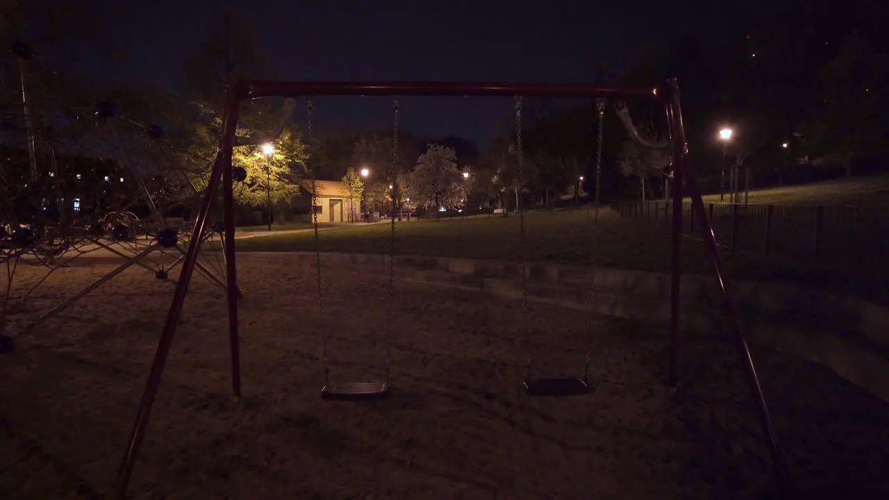 Moving swing set seats empty children playground at night Prague Czechia lockdown