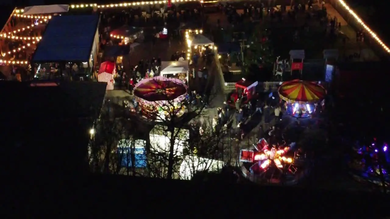 Variety Illuminated Christmas fairground festival in neighbourhood car park at night aerial view