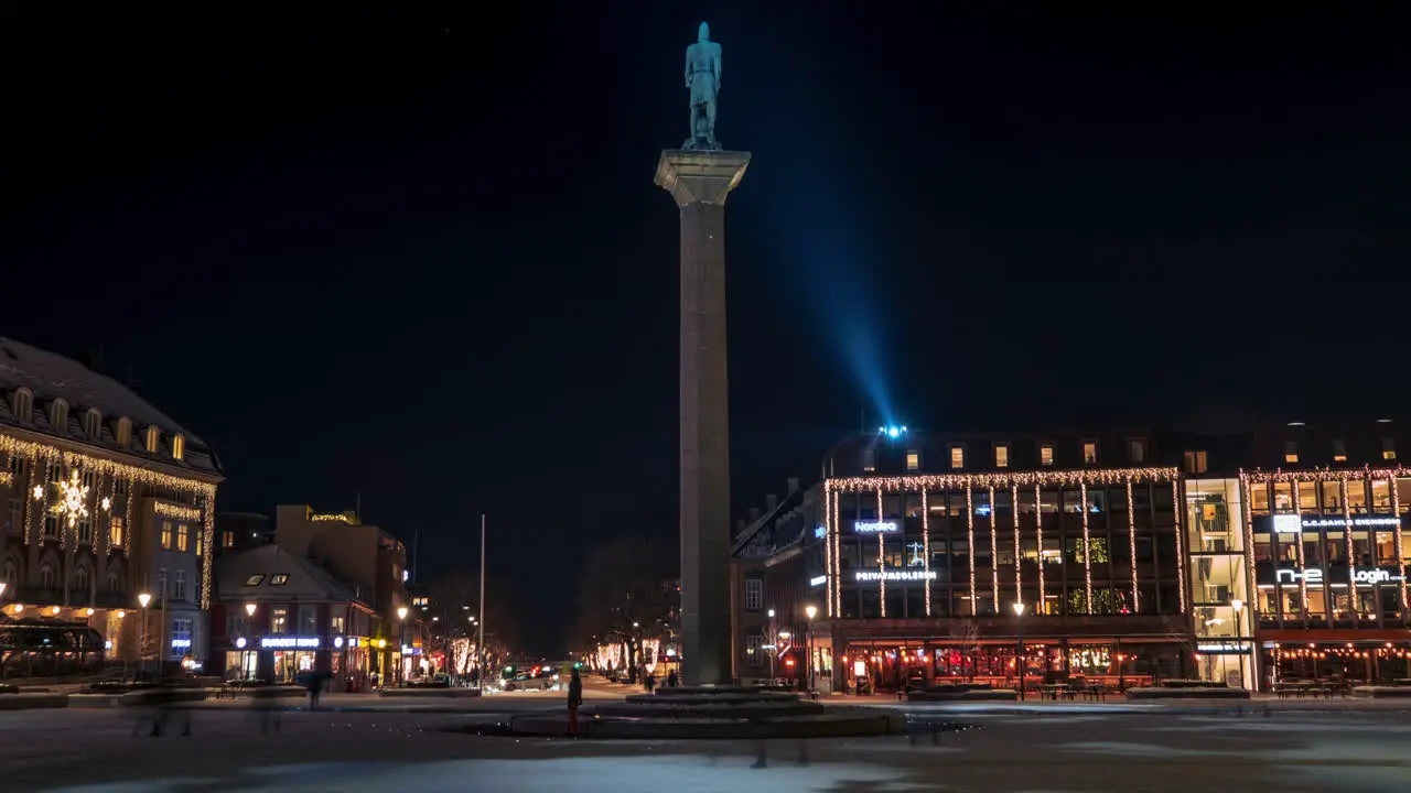 People walking across Trondheim City Square in Nighttime showing the statue of Olav Tryggvason in the middle of the city center