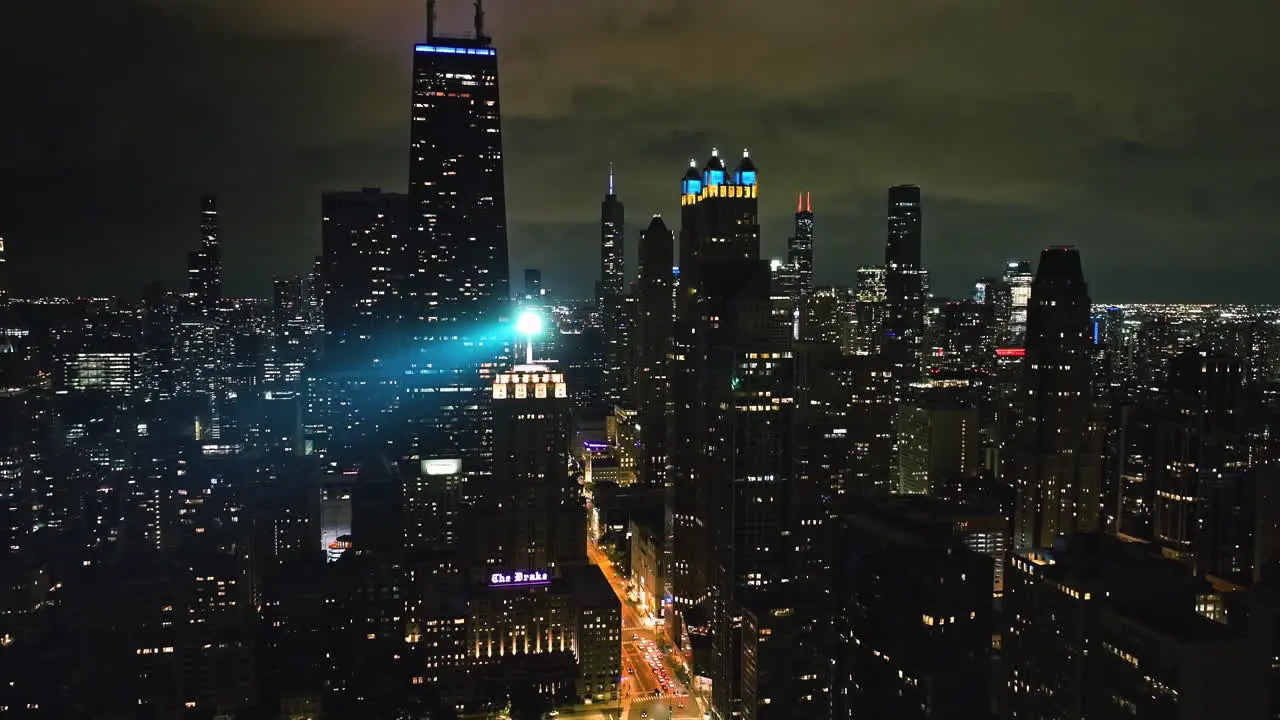 Aerial view backwards away from the night lit Chicago skyline pull back drone shot