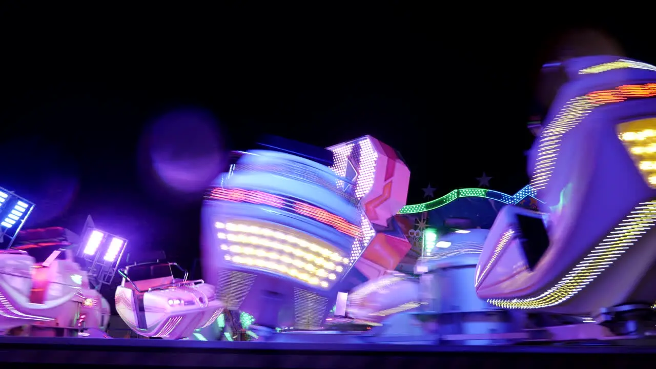 Crazy fast spinning illuminated carousel outdoor at night in fun fair park close up