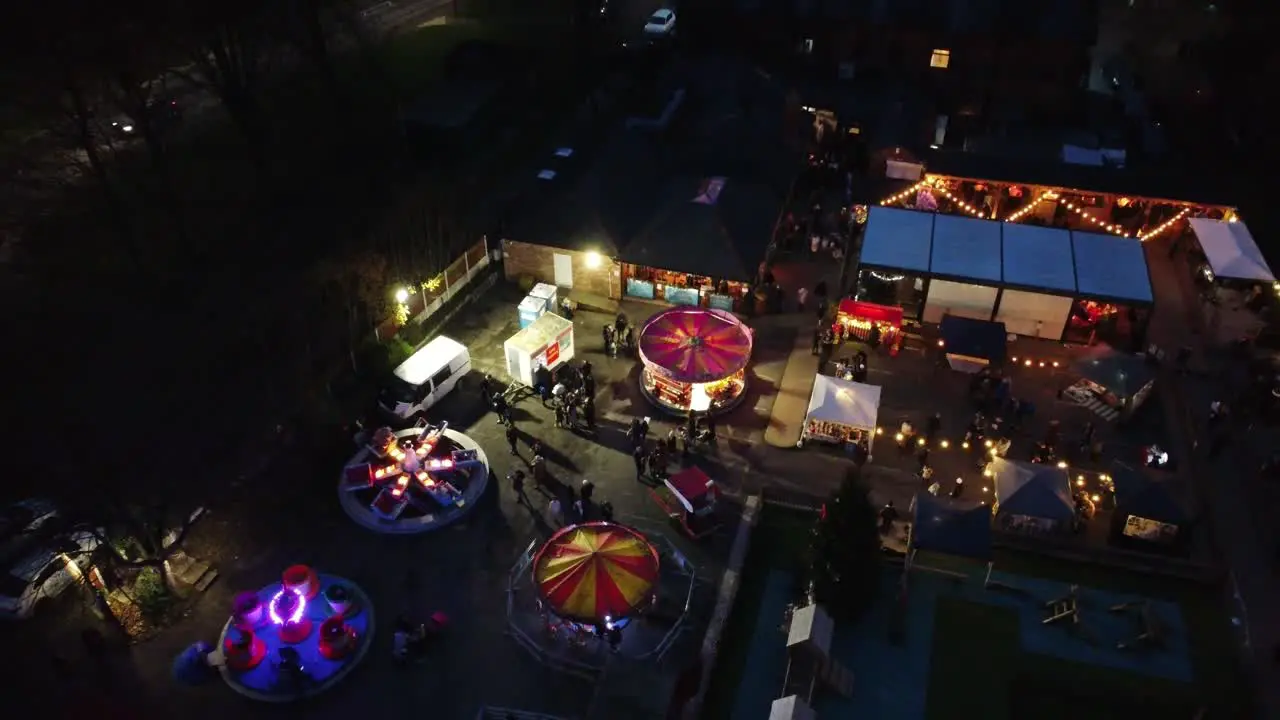 Illuminated Christmas fairground festival in neighbourhood car park at night aerial view