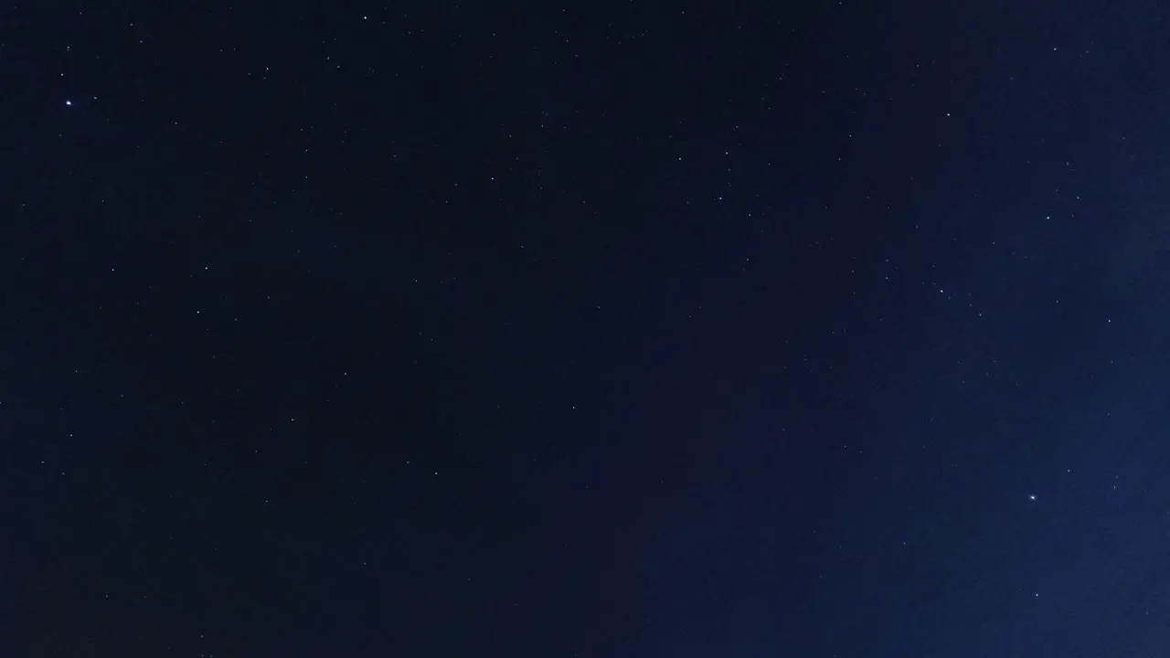 Time lapse looking up at clouds passing sparkling stars in the clear night sky