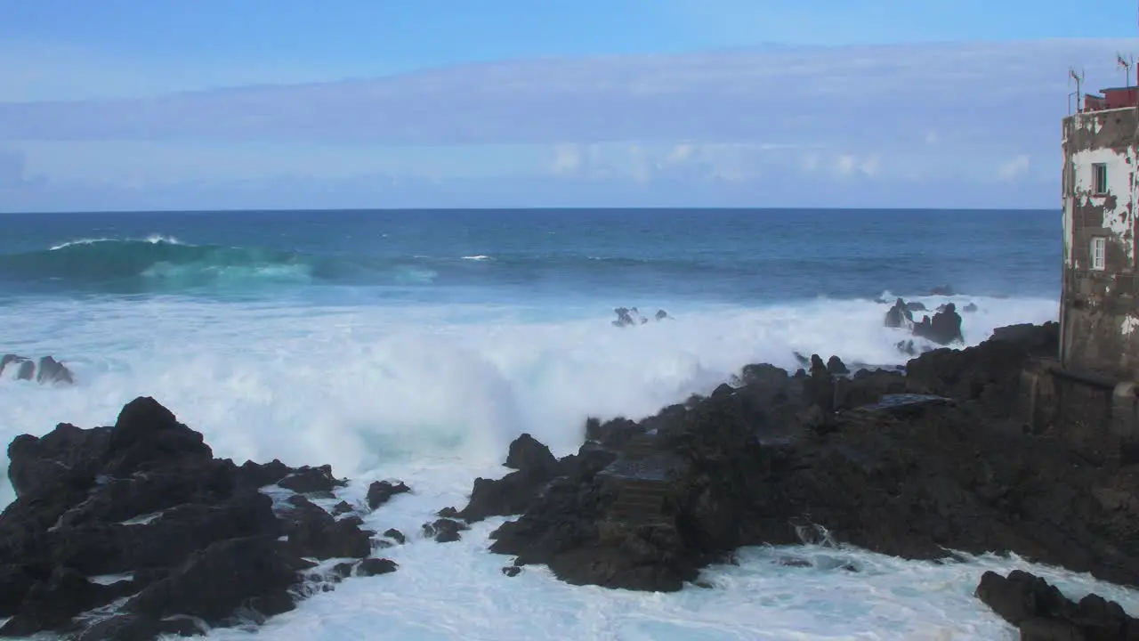 A big waves of the Atlantic Ocean breaks on a rocky coast on a sunny day during a storm in Puerto de la Cruz in the Canaries  wide angle handheld shot