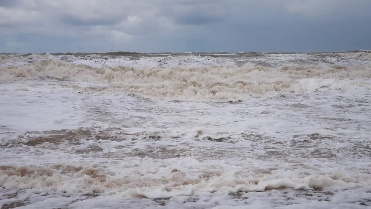 Harsh stormy rolling coastal threatening ocean waves foam blowing in rough windy weather