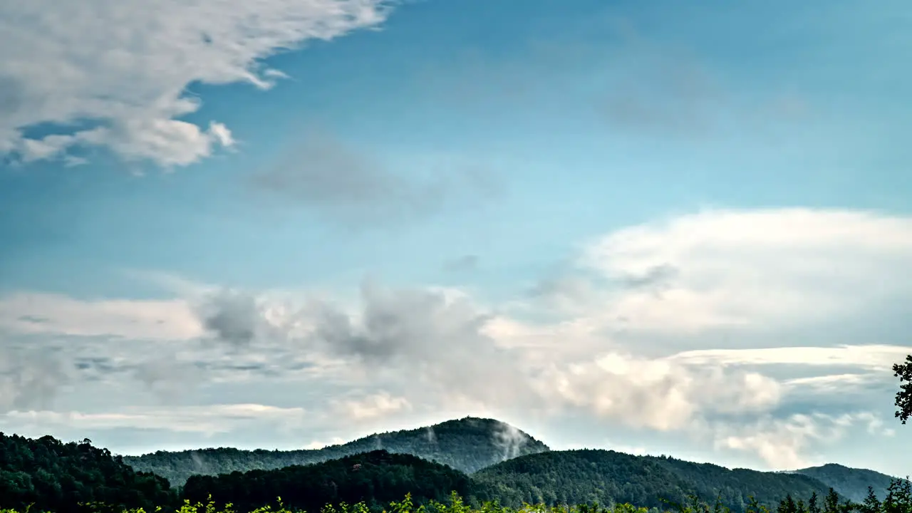 Timelapse of different layers of clouds moving fast and slowly above european wooded hills 4K