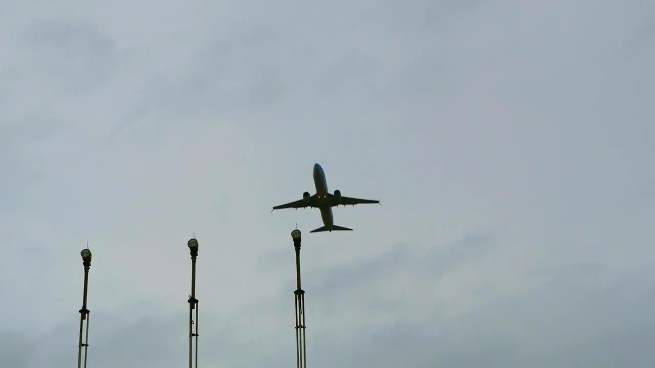 Slow motion of an aircraft passing over aeronautical lights with a grey sky