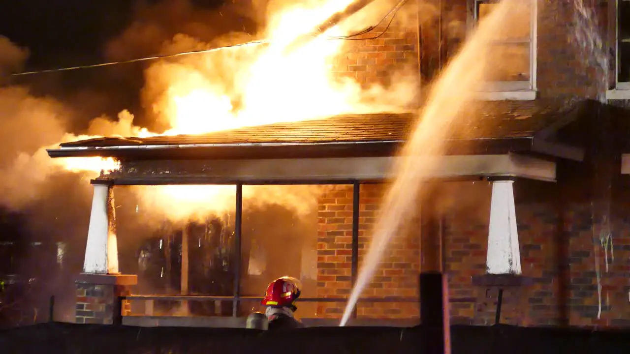 Firefighters try to extinguish a burning house at night