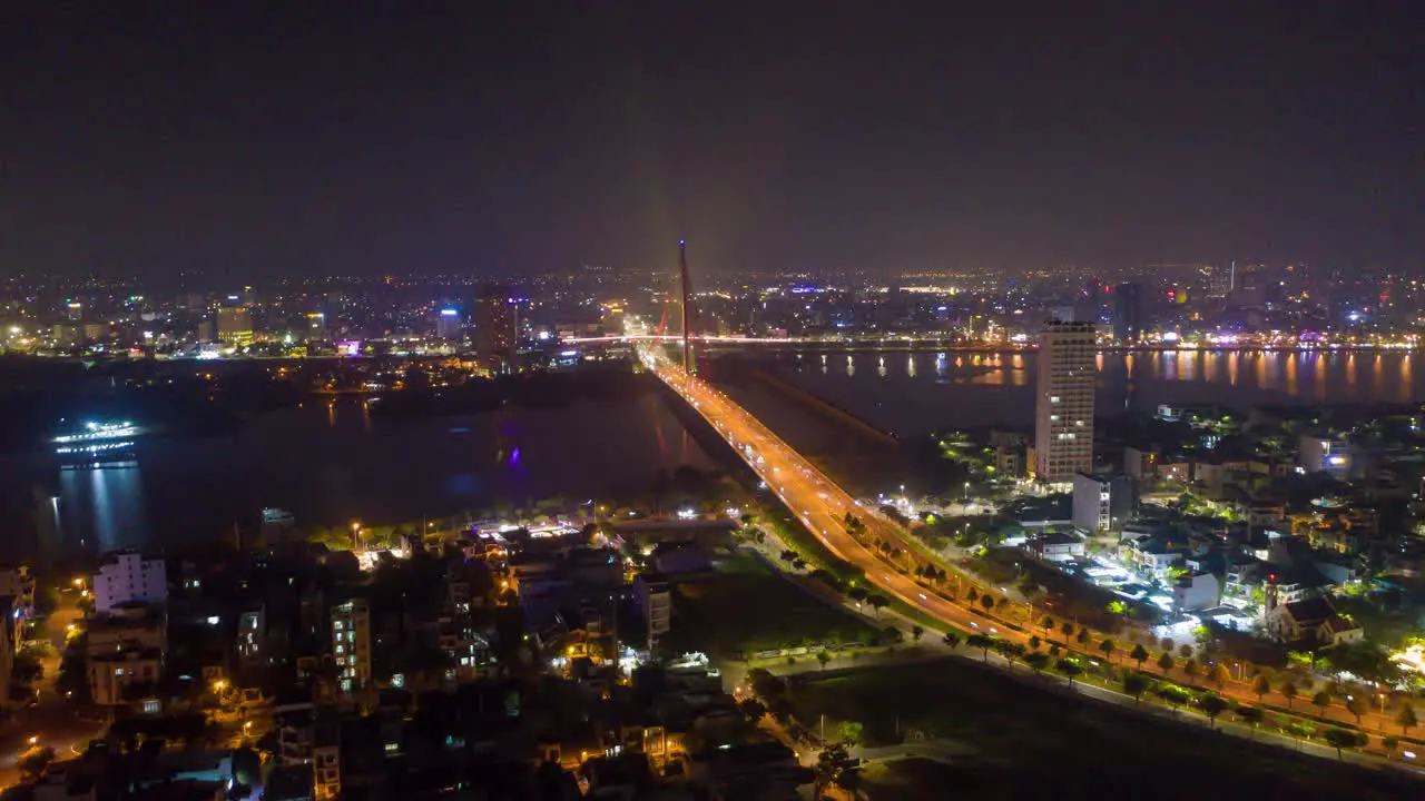 Stunning colorful aerial night time lapse of iconic landmark Tran Thi Ly Bridge traffic and city skyline changing colors in Danang Vietnam