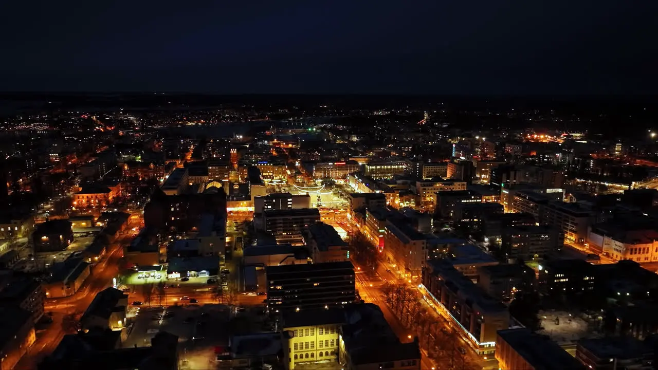 Drone shot circling the illuminated downtown of Vaasa winter night in Finland