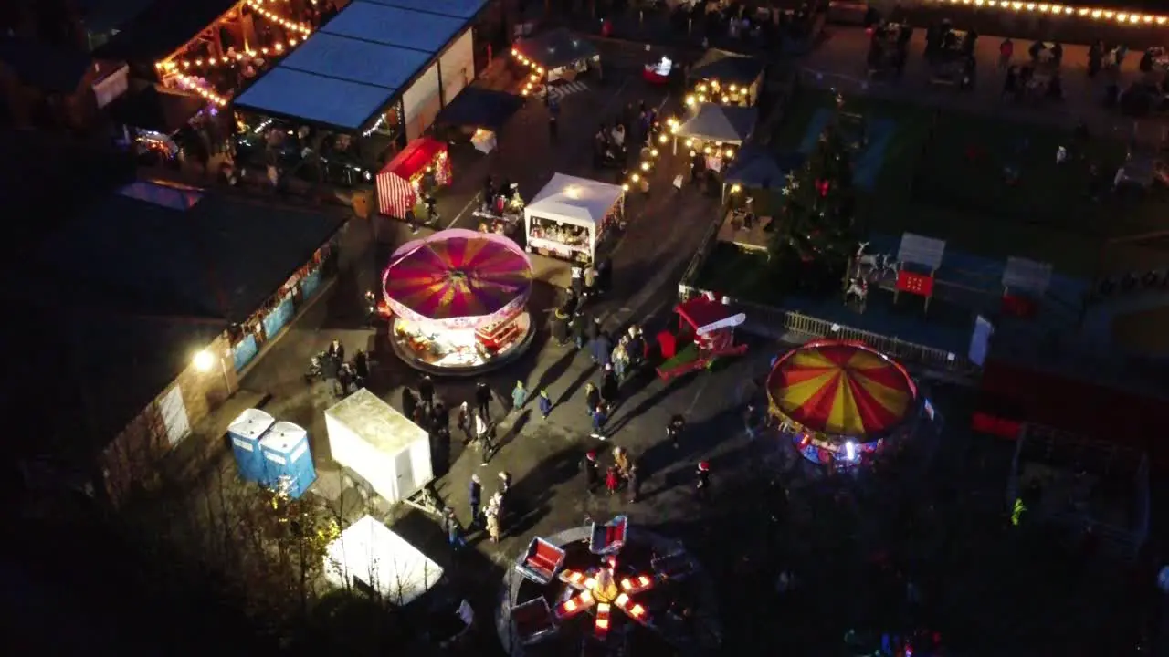 Illuminated Christmas funfair festival in neighbourhood car park at night aerial view