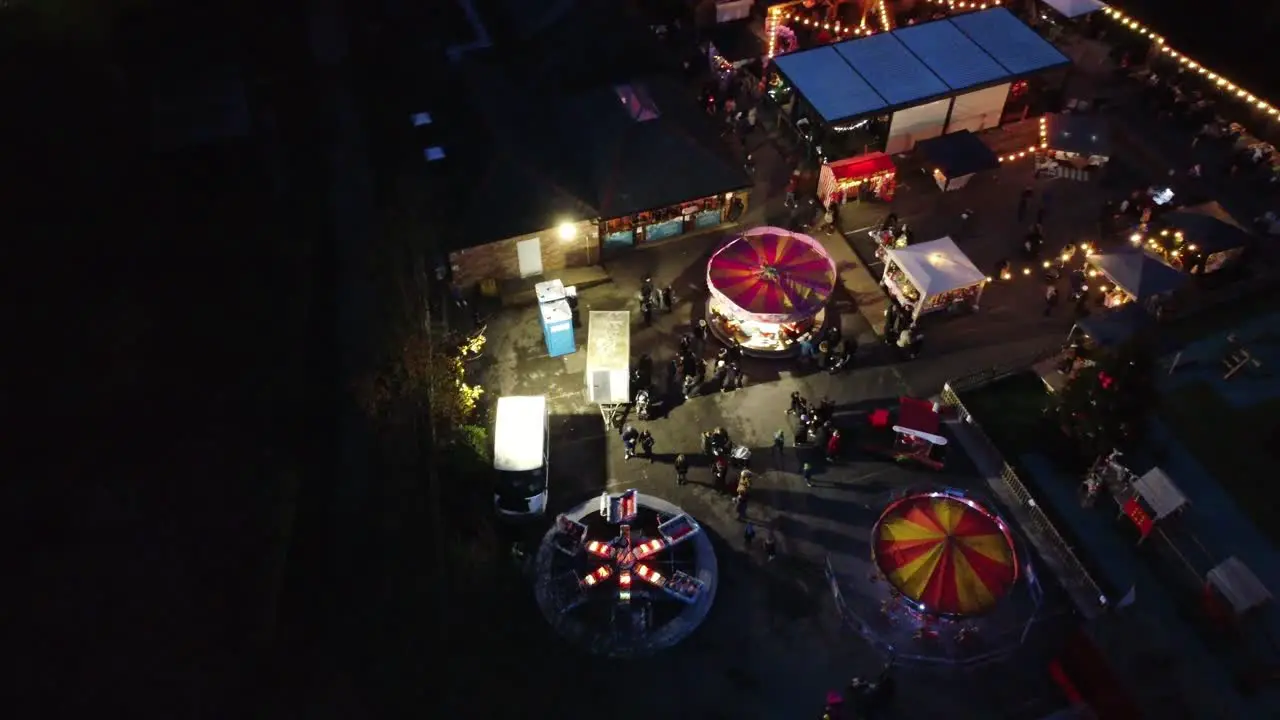 Illuminated Christmas funfair attraction in neighbourhood car park at night aerial view