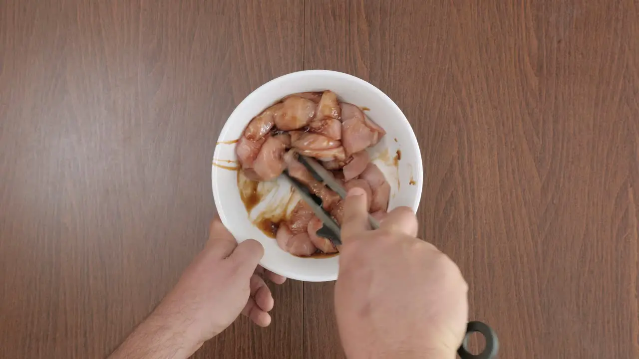 Man seasoning chicken with soy sauce