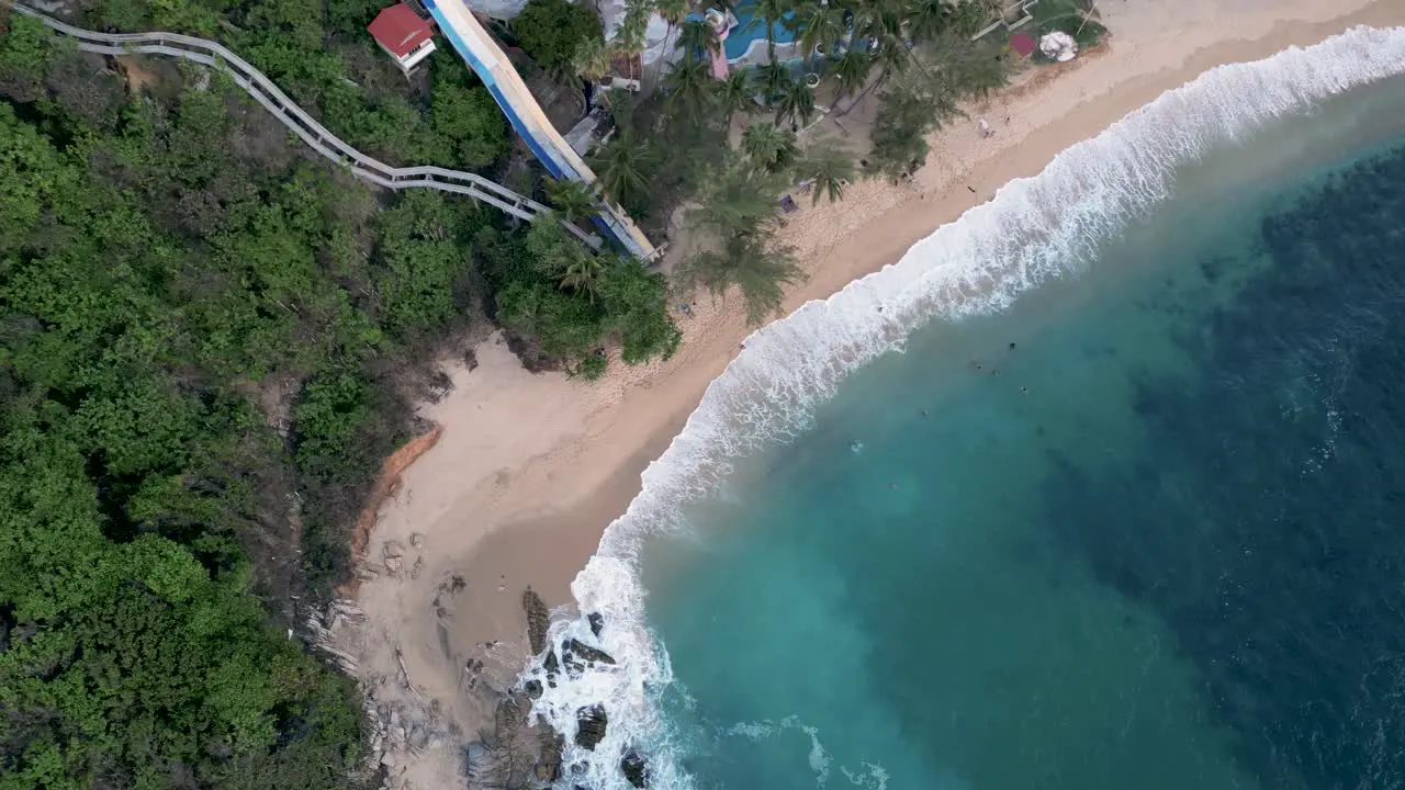 A bird's-eye view of Coral Beach clear sandy shores and deep blue waters with powerful waves