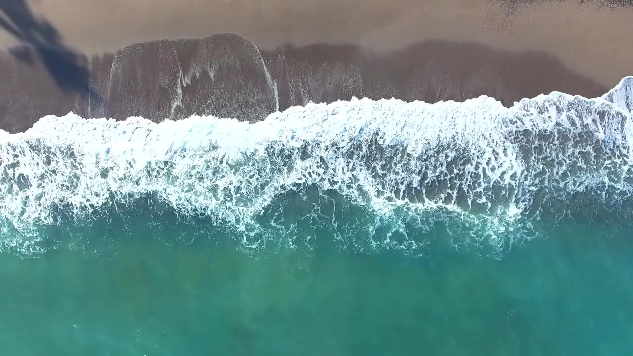 Aerial view waves crashing on tropical beach sand