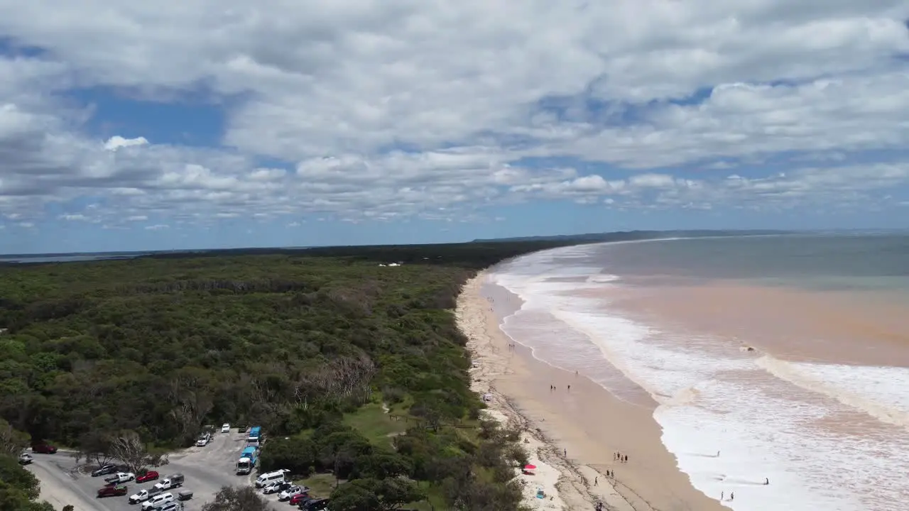 Flying over a carpark towards a muddy beach after a storm