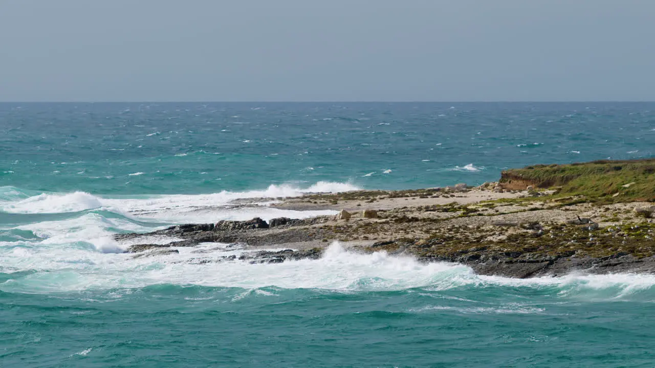 Big waves crushing on Fenoliga island with seagulls on cloudy stormy weather