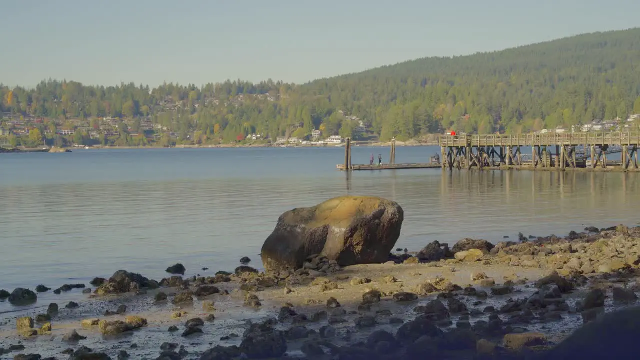 Giant rock on shoreline surrounded by scattered rocks surrounded by water