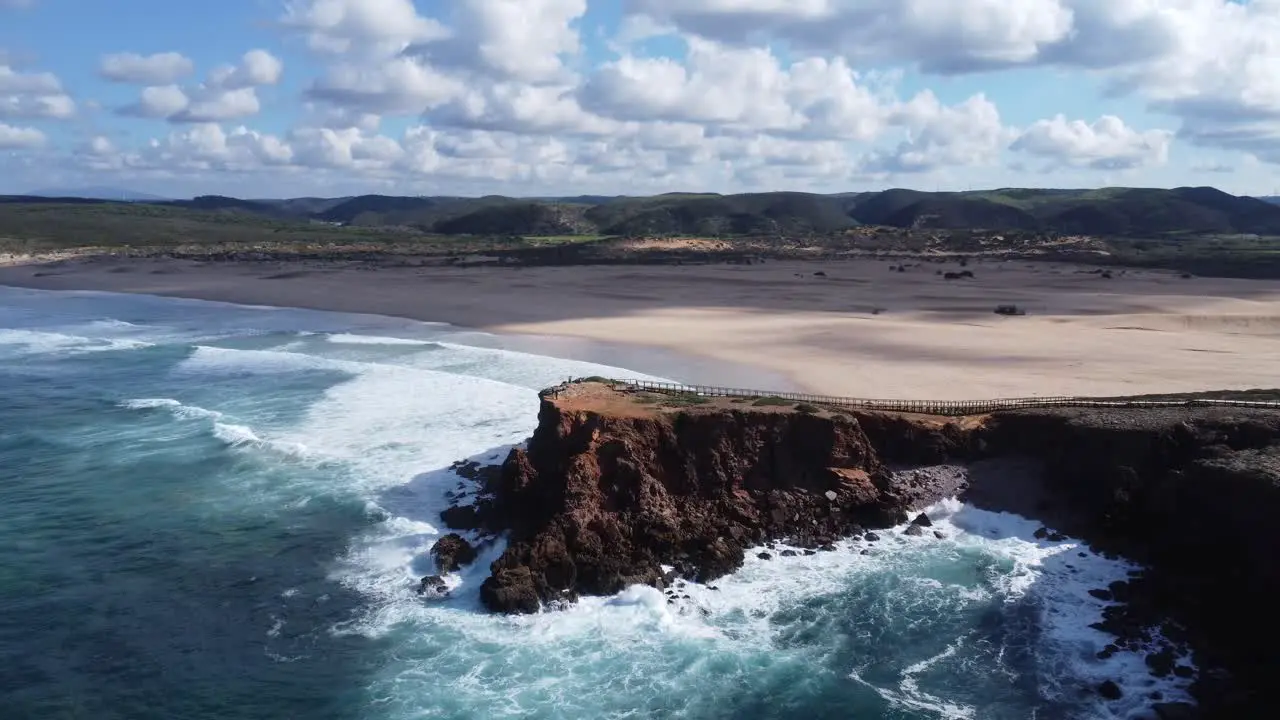 drone flies over cliff at stunning bordeira beach in sothern portugal perfect weather with some nice little clouds