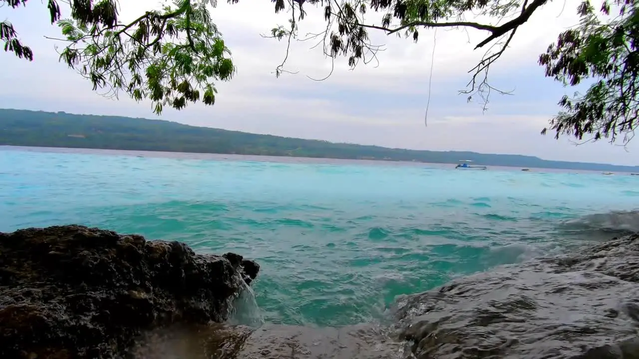 blue waters huge waves splashes into the rocks with an island view