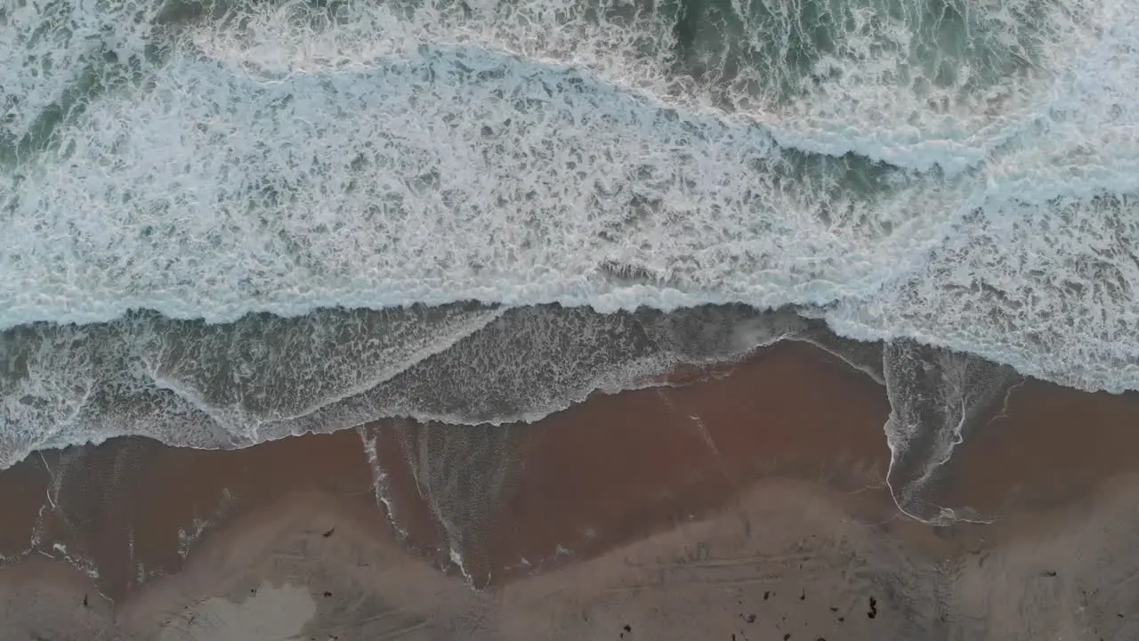 Calm waves crashing on beach drone shot