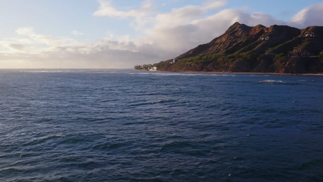 Aerial footage across the blue Pacific ocean water with Diamond Head volcanic mountain formation on the island of Oahu Hawaii on a sunny day