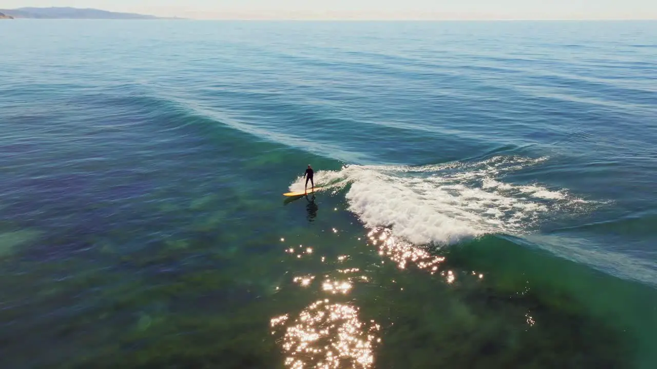 Surfer Riding Blue Ocean Wave In San Diego California USA aerial drone shot