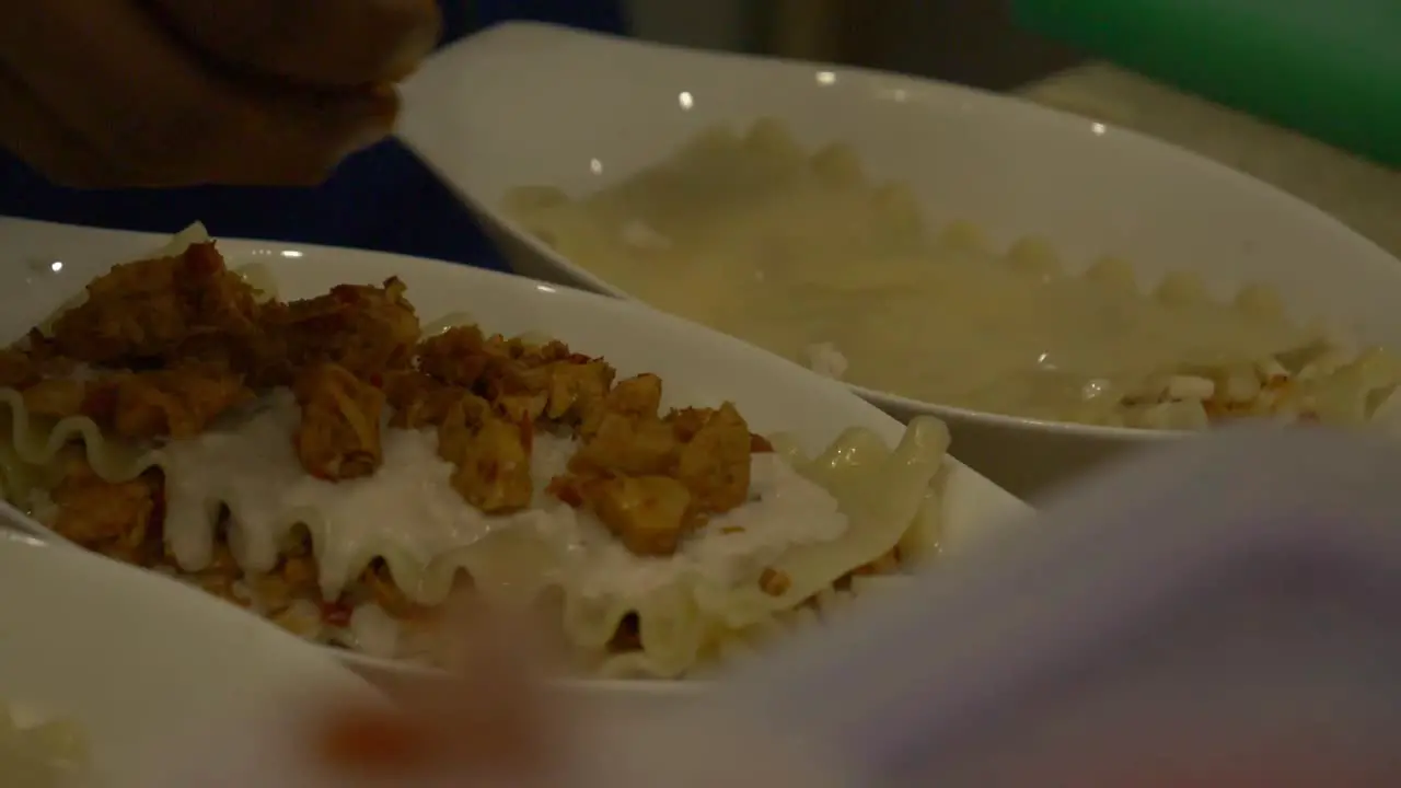 Chicken Pieces Being Sprinkled By Hand On Top Of Lasagne