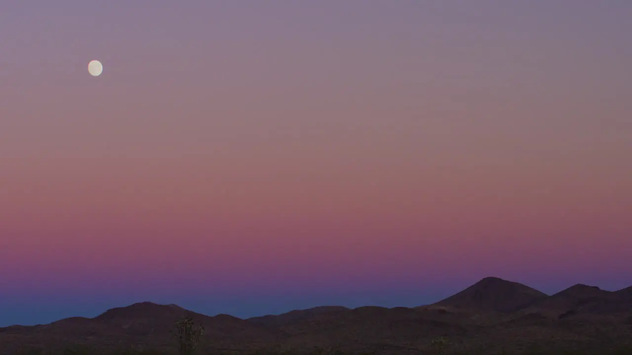 Moonrise during colorful purple sunset in the desert hills of Las Vegas Nevada